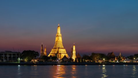 Wat Arun Ratchawararam (Temple of Dawn) and five pagodas during twilight, famous tourist destination in Bangkok, Thailand; day to night, zoom out - time lapse