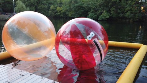 Russia, saratov - July , 2021. Little children in an inflatable balloon, having fun on the water. The ball in the water - fascinating summer attractions for children. Water zorbing.