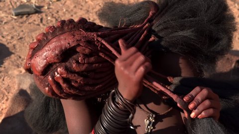 Closeup of Himba woman doing her hair in traditional Himba village near Kamanjab in northern Namibia, Africa. 