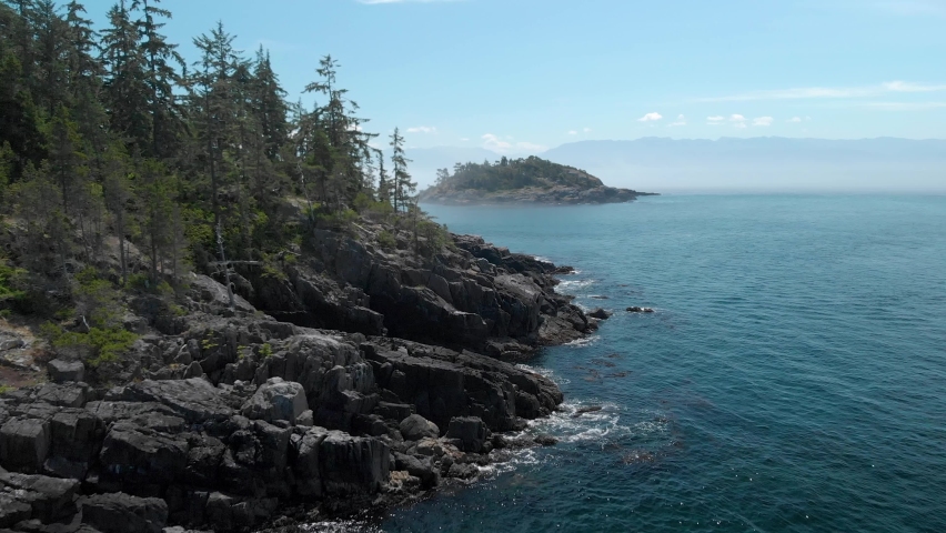 A aerial drone shot of the beautiful coastline with turquoise water near Sooke, BC. 4K 24FPS. Royalty-Free Stock Footage #1077242564