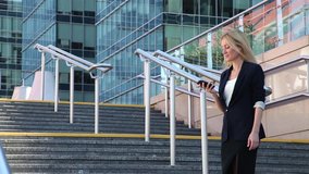 Business woman standing on the stairs and talking on a cellular phone amid office building
