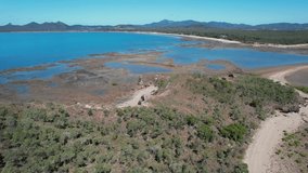 Aerial footage of coastline at low tide showing flats and shallow water. Seaforth, Queensland, Australia
