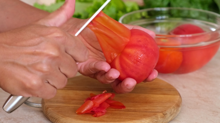 Peeling red tomatoes. Skin Removal process from tomato in glass bowl. Cooking vegetarian food, cooking food in the kitchen.