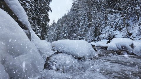 Winter Tale. Winter landscape with snowy forest, cold river with ice and snowfall. Winter nature background, gimbal shot