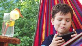 boy resting in a hammock in nature, drinking a cocktail with lemon, talking on the phone, taking a selfie. teenager Relaxing In Hammock. - Powered by Shutterstock - Get 15% off with code: PIKWIZARD15