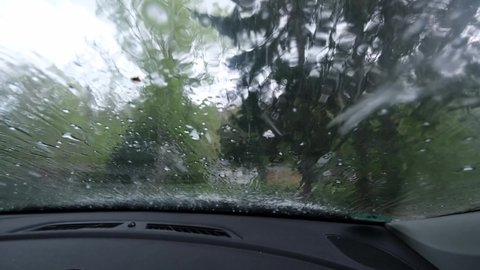 Hailstones hitting a car windscreen. Driving in bad conditions, huge summer hailstorm. Unpredictable weather conditions, solid precipitation, climate change concept. Car damage from ice, close up 4k