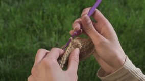 Close up of female hands knitting camel wool. 4K resolution. Handmade crochet close-up. Crochet woolen threads. Swoosh pattern in split. Hands close-up 