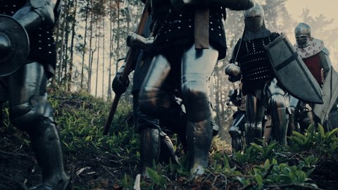 Epic Invading Army of Medieval Soldiers Marching Through Forest. Armored Warriors with Swords Moving to Battlefield. War, Battle, Crusades in Dark Ages. Cinematic Historical Reenactment. Low Angle
