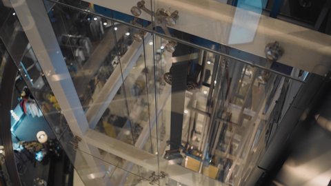 The elevator moves along a transparent shaft in a shopping center. The camera monitors the operation of the mechanism
