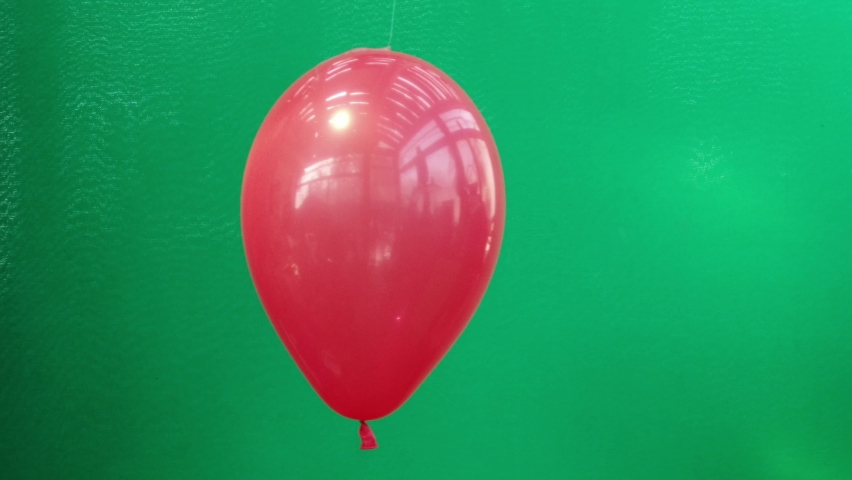 A red balloon on a green background bursts and smoke comes out of it