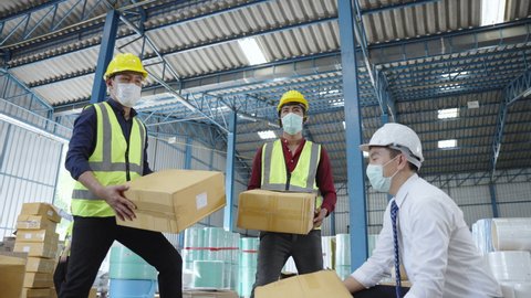 the workers wearing protective face mask and working in the warehouse during COVID-19 pandemic. the concept of coronavirus, shipping, logistics, business and transportation 