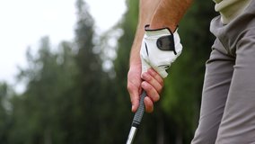 Hands of a playing man holding a golf club