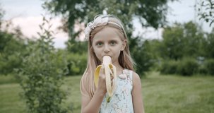 Portrait of cute little girl without a tooth smiling while eating banana 