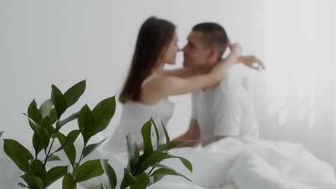 Young Passionate Couple Kissing In Bed, Affectionate Lovers Enjoying Foreplay In Bedroom, Man And Woman In Underwear Having Intimate Moments, Slow Motion Footage With Selective Focus