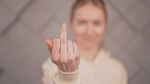 defocus woman showing hand gesture fuck holding the middle finger towards someone slow motion