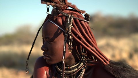 Closeup shot of beautiful young Himba woman wearing traditional jewelry and headpiece at her village near Kamanjab in northern Namibia, Africa. 