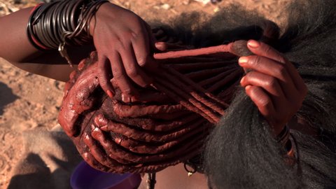 Closeup shot of Himba woman doing her hair in traditional style at her village near Kamanjab in northern Namibia, Africa. 