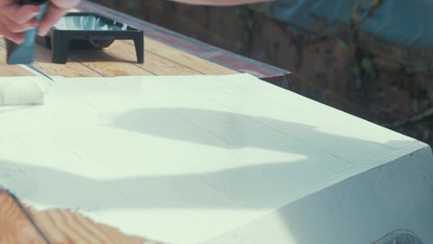 Applying white primer paint on wood boat wheelhouse cabin roof planks