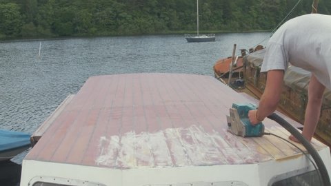 Timelapse of Young carpenter ring varnish on wooden boat wheelhouse roof