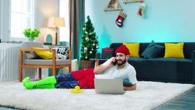 Large spacious living room a man using the laptop to order something online and take the phone to make a call happy and excited he speaking on the phone