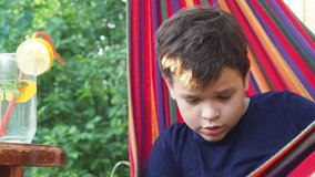boy resting in a hammock in nature, drinking a cocktail with lemon, talking on the phone, taking a selfie. teenager Relaxing In Hammock. - Powered by Shutterstock - Get 15% off with code: PIKWIZARD15