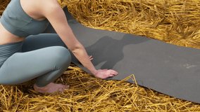 Woman preparing carpet for yoga practice on wheat field
