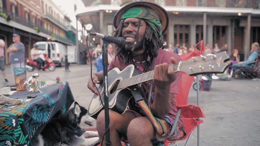 Busker playing on guitar on the street in slow motion. New Orleans, Louisiana, USA. 23 June 2019 