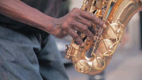Elderly black male busker playing saxophone on the street in slow motion. New Orleans, Louisiana, USA. 23 June 2019 