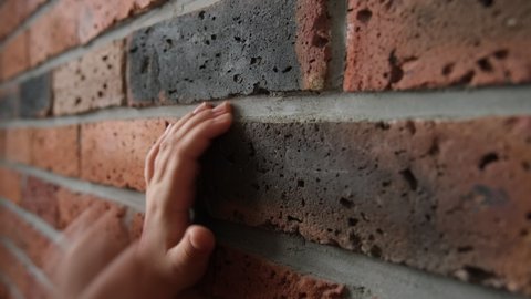 Scared Desperate Kidnapped Imprisoned Caucasian Kid Scratching and Hitting Red Brick Wall with Bare Fingers Hands and Nails Calling For Help in Panic