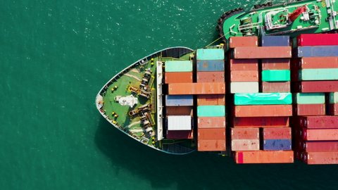 Aerial top view cargo logistics container ship floating in green sea, business and industry service transportation import export international worldwide by shipping containers ocean flight 4k video 
