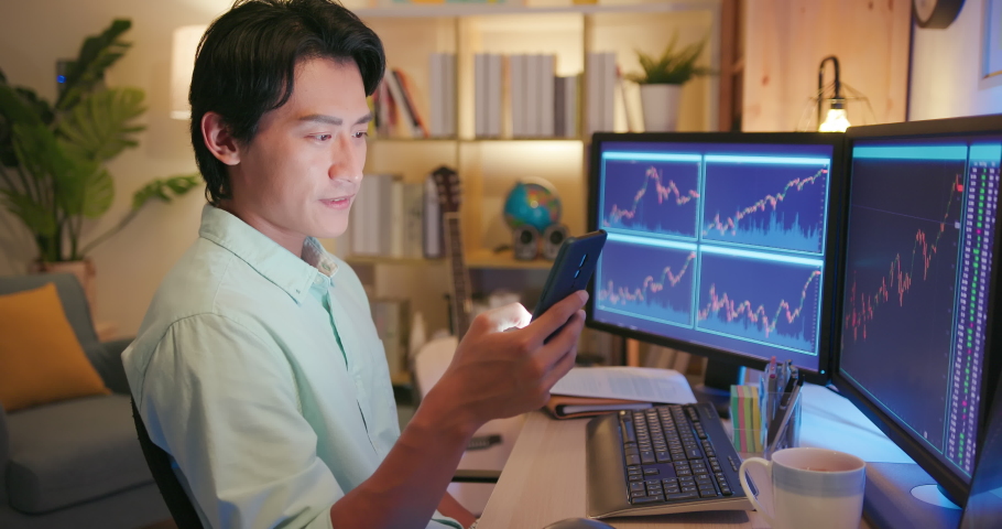 asian man has stock market or cryptocurrency investment from home by computer and mobile phone with coffee Royalty-Free Stock Footage #1077297293