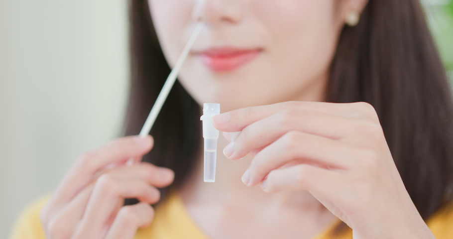 Covid-19 rapid antigen self test process - close up of smiling asian woman placing nasal swab inside the tube with liquid Royalty-Free Stock Footage #1077297434