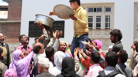 SRINAGAR, INDIA - JUNE 11, 2015: Unknown Indian man feeds the hungry people near a Muslim mosque. Kashmiris are fighting for their freedom for 20 years now. Kashmir became dangerous again.