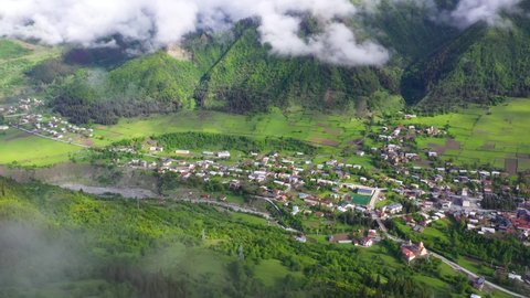 Aerial: Mestia highland town, view through clouds in Caucasus Mountains, Georgia
