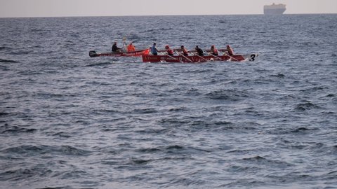 Livorno, Italy - july 2021: Red Rowing Boat with ten Oars during a Training in the Sea before a Sports Competition - slow motion