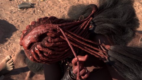 Closeup shot of Himba woman doing her hair in traditional style at her village near Kamanjab in northern Namibia, Africa. 