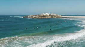 Baleal, Portugal, Europe. People swimming on a surfing boards along the coastline. Aerial view of idyllic beach washed with bluish ocean. High quality 4k footage