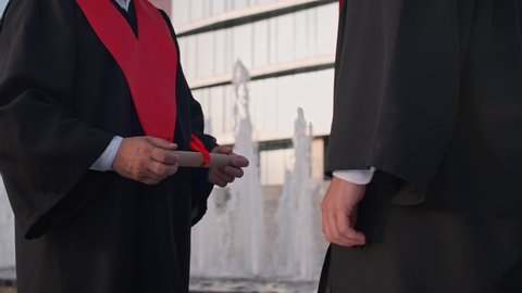 Graduation ceremony, senior lecturer presents a diploma to a university graduate, a solemn moment, handshake, 4k slow motion.