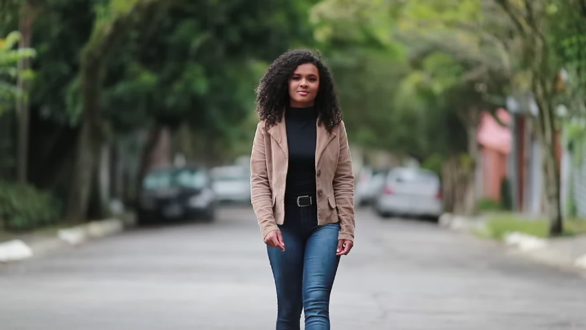 Young black woman walking forward. Confident African ethnicity girl walks towards camera