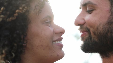 Hispanic couple kissing outside with lens-flare. South American lovers eskimo kiss