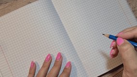 A woman's hand draws a heart with a pencil in a notebook