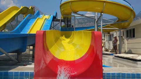 KEMER, TURKEY - JULY 22, 2021: family weekend in the water park, active mom and little son with inflatable oversleeves go down the slide into pool