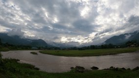 Time-lapse video of the river landscape. clouds moving, sunset, mountains until the sky is overcast A wide area of ​​green grass farm