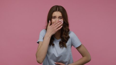 Amused teenager girl pointing finger at camera and laughing out loud, holding belly with hilarious laughter, making fun of ridiculous appearance, joke. Indoor studio shot isolated over pink background