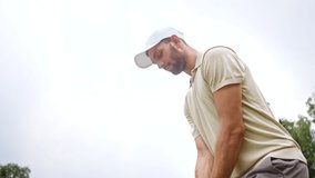 Young golfer in a cap hitting a golf ball with a golf club on the background