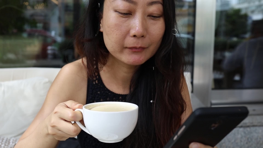 Asian Woman Drinking Coffee And Chatting On Smartphone