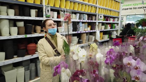 Woman chooses orchid flowers in the store. Store warehouse of materials for the improvement and repair of houses and countryside suburban areas Leroy Merlin. Perm, Russia, April-18,2021.
