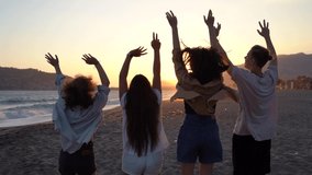 Side view of a group of young friends enjoying time in the sunset on a tropical beach, embracing, laughing and walking. Slow motion. - Powered by Shutterstock - Get 15% off with code: PIKWIZARD15
