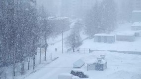 Urban landscape in blue colors with heavy snowfall on the street. Houses, people and roads in winter. Blizzard, snowstorm and big snowflakes falling from the sky. Cold freeze weather. Poor visibility. - Powered by Shutterstock - Get 15% off with code: PIKWIZARD15