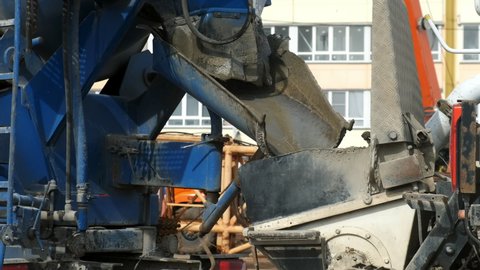 Repair and maintenance of construction equipment on the building site. Washing the troughts of the concrete mixer with water on construction site, closeup view.